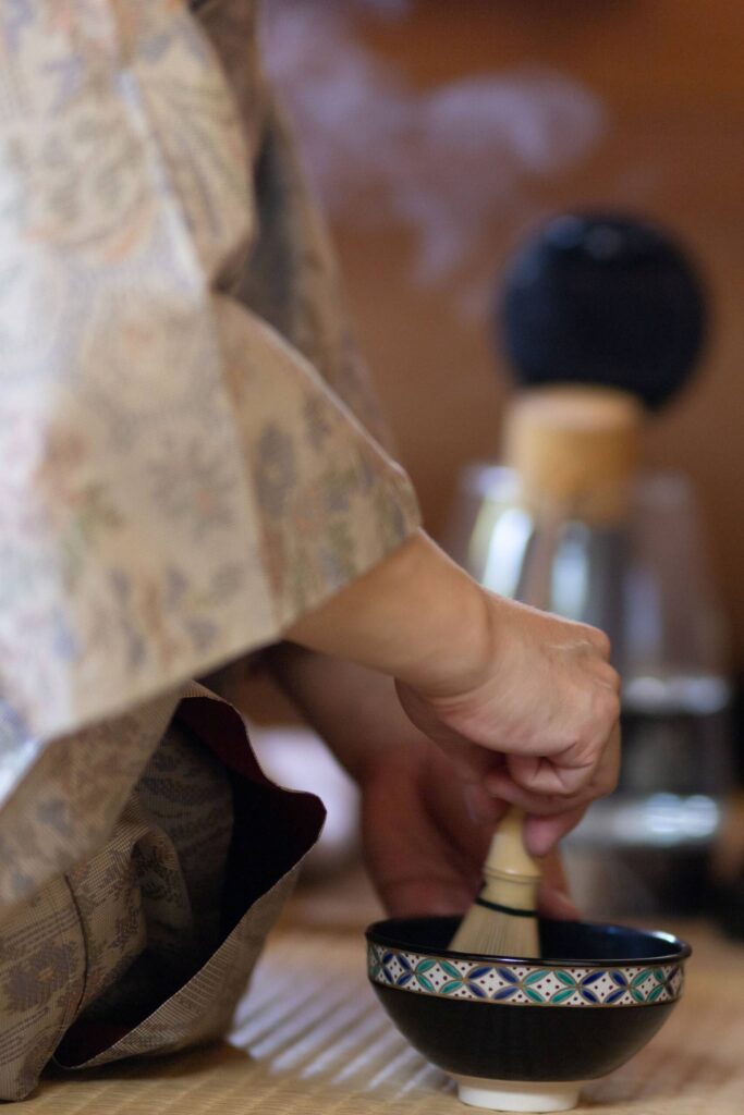 Decorative image displaying a woman's hand whisking matcha